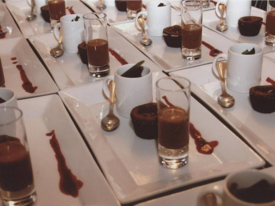 A table set with multiple plates of chocolate desserts, each accompanied by a spoon and a glass.