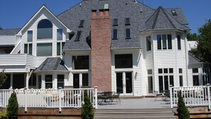 A large, multi-story house with a prominent brick chimney, multiple windows, and a covered patio area with outdoor furniture. - The Columbia Inn at Peralynna Manor (Columbia)