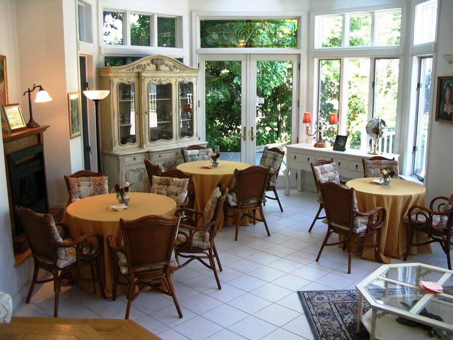 Comedor con mesas y sillas redondas, una mesa de centro con cubierta de vidrio y una chimenea.