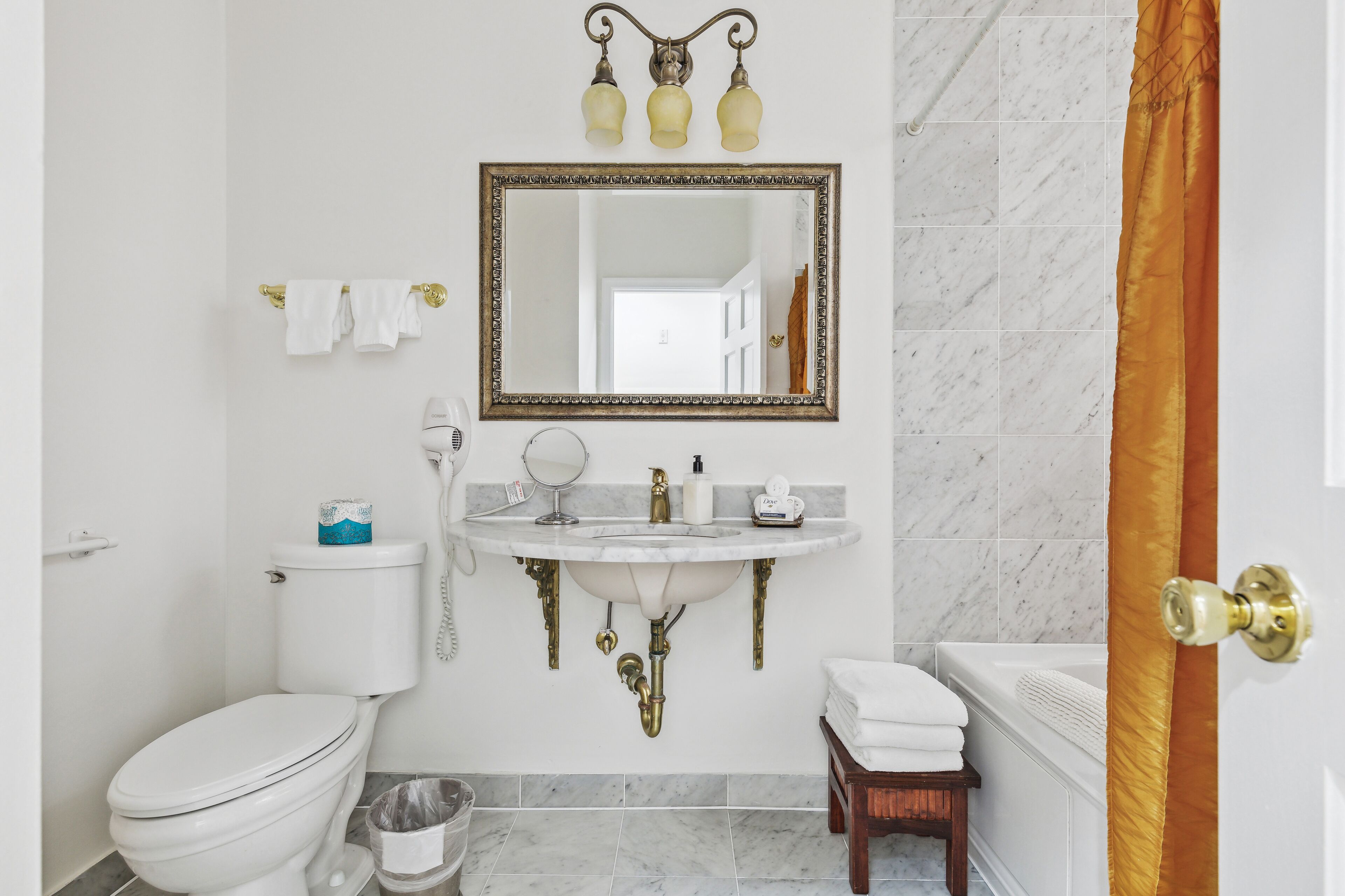 A bathroom with a toilet, sink, mirror, and bathtub.