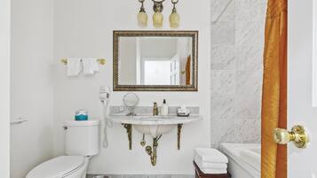 A bathroom with a toilet, sink, mirror, and bathtub.