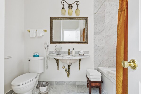 A bathroom with a toilet, sink, mirror, and bathtub.