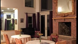 A dining area with round tables and chairs, a fireplace, and a large mirror on the wall. - The Columbia Inn at Peralynna Manor (Columbia)