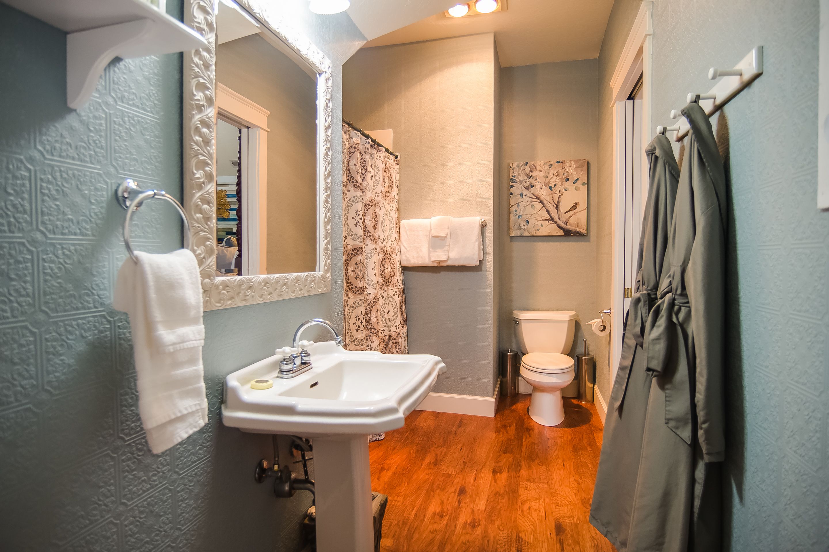 A bathroom with a white sink, a mirror, a shower curtain, and a toilet.