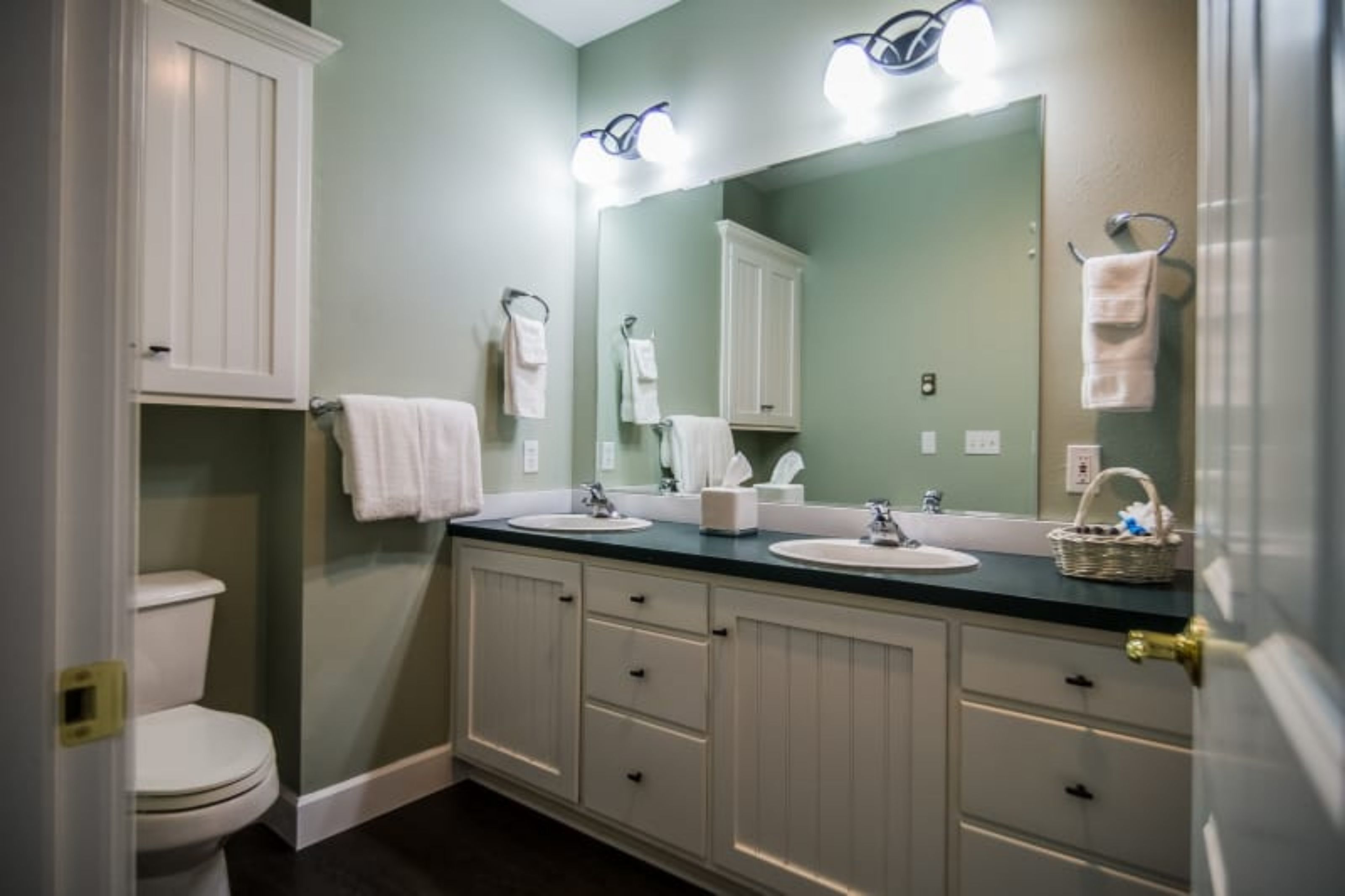 A bathroom with two sinks, a toilet, and a large mirror.