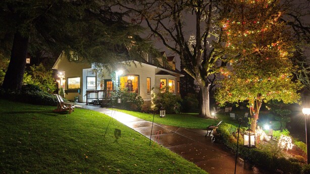 Una casa con un porche bien iluminado y un camino que lleva a la entrada.