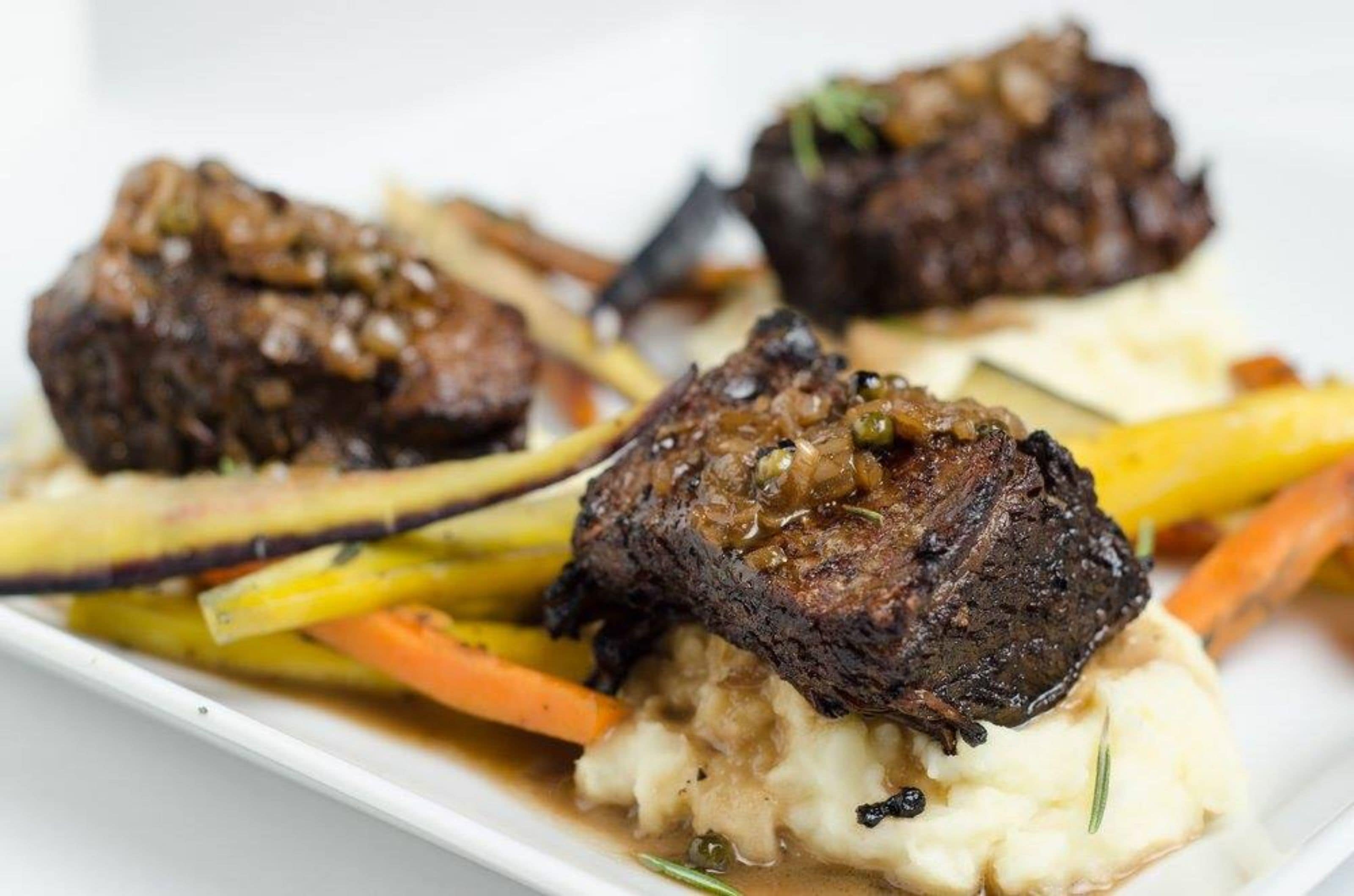 A dish with beef, vegetables, and mashed potatoes.