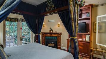 A bedroom with a large bed, a fireplace, a television, and a bookshelf.
