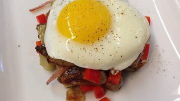 Un plato cuadrado blanco con un huevo frito sobre una guarnición de verduras y carne salteadas.