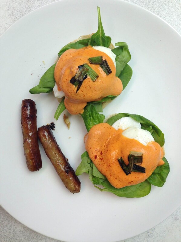 A plate with two poached eggs on spinach leaves, accompanied by grilled sausages.