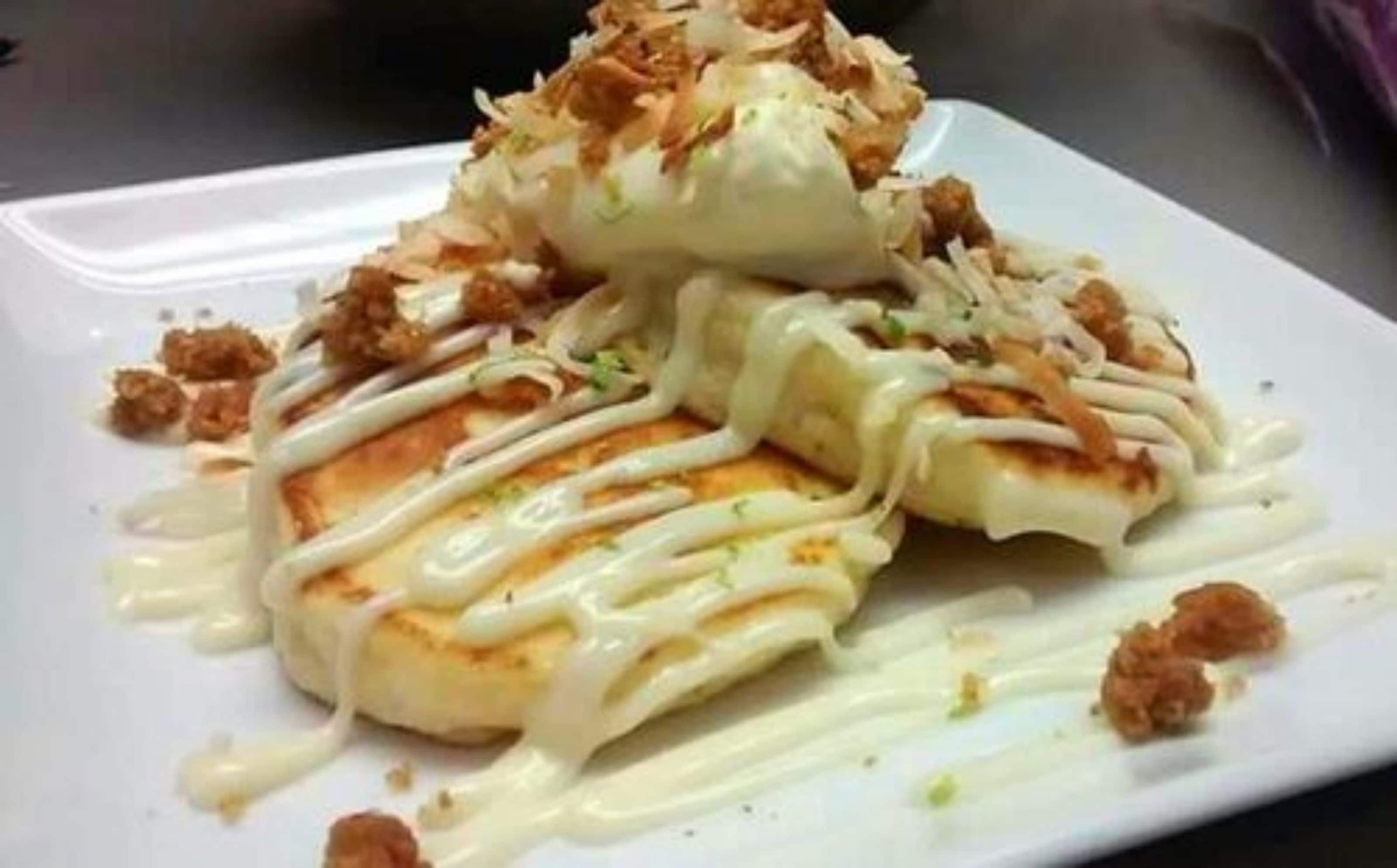 A plate of food with a white sauce and shredded toppings.
