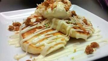 A plate of food with a white sauce and shredded toppings.