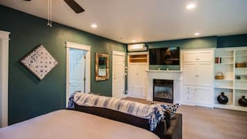 A bedroom with a bed, a ceiling fan, a fireplace, and built-in storage cabinets.