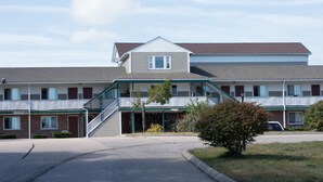 A motel with a central entrance, a covered walkway, and a parking area. - Budget Inn North Stonington (North Stonington)