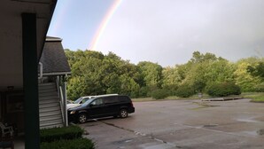 A parking area with a black SUV parked near a building with a green roof. - Budget Inn North Stonington (North Stonington)