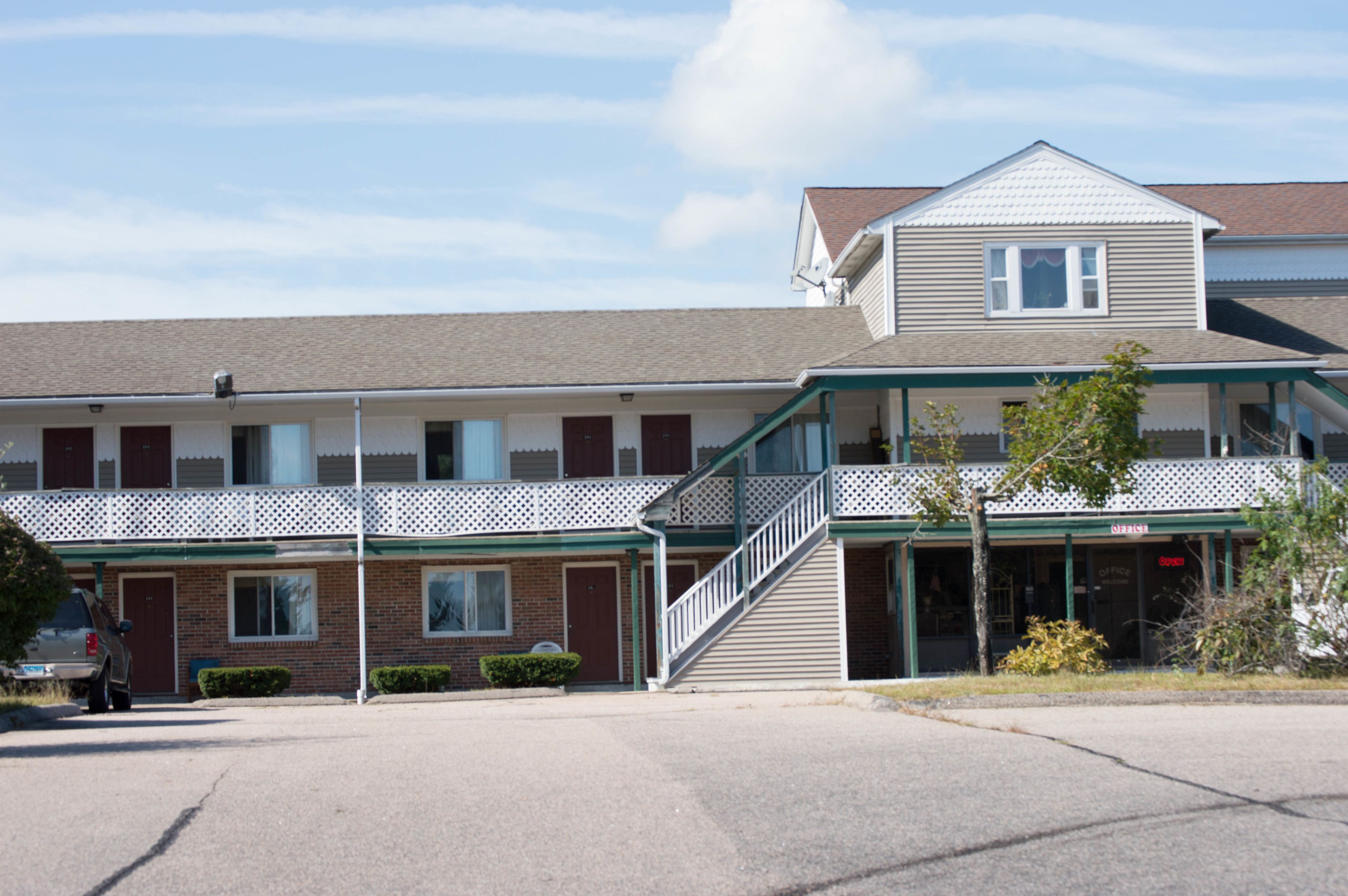 A two-story motel with a covered front porch, a staircase leading to the second floor, and a parking lot in front.