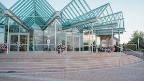 A modern building with a glass facade and a geometric roof structure. - DEKRA Congresshotel Wart (Altensteig)