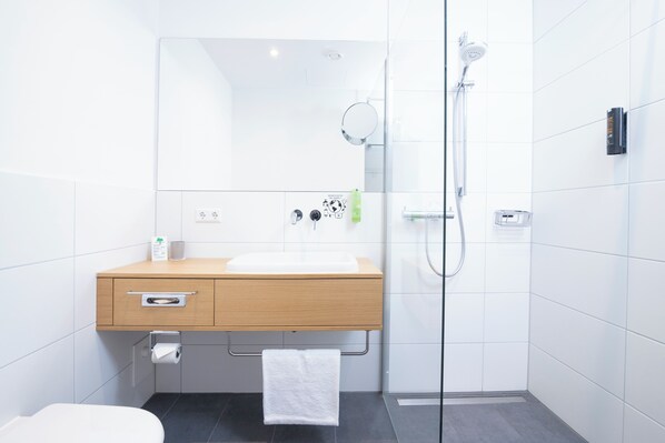 A modern bathroom with a wooden vanity, a glass shower enclosure, and a white toilet.