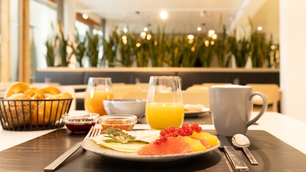 A breakfast setting with a plate of food, a glass of orange juice, and a mug on a table. - DEKRA Congresshotel Wart (Altensteig)