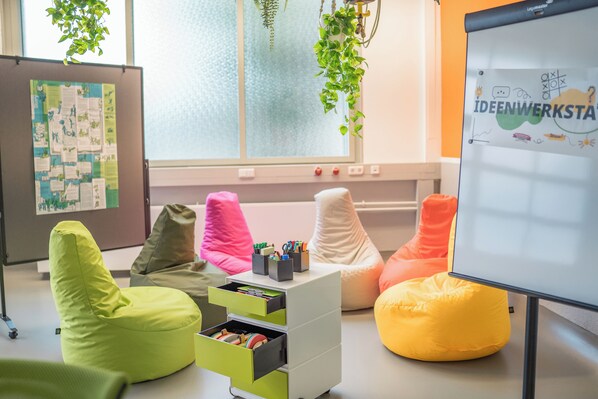 A modern workspace with bean bags, a whiteboard, and a bulletin board.