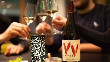 A bottle of wine with a label, glasses, and a patterned candle holder on a table.