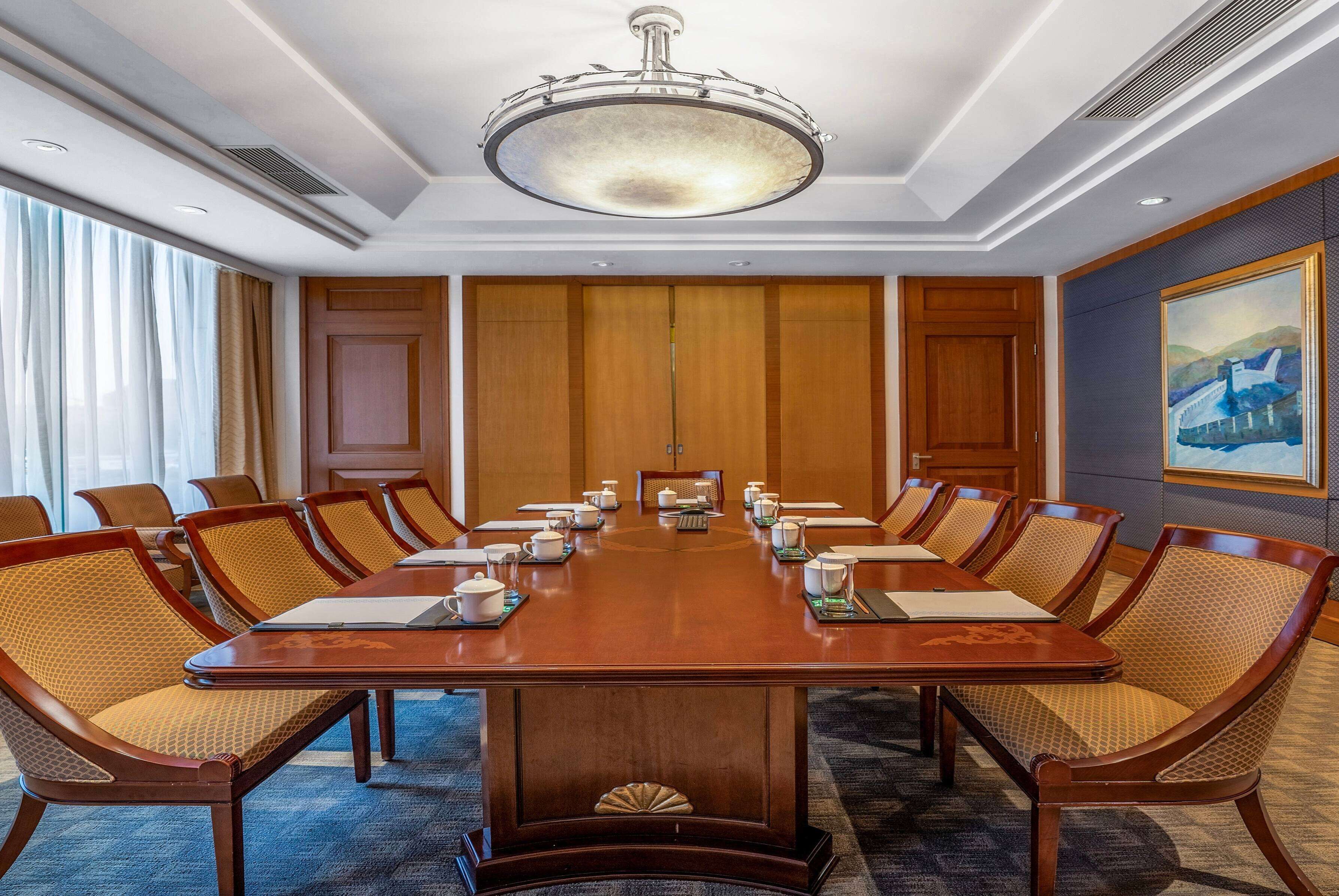 A conference room with a large wooden table, matching chairs, and a chandelier.