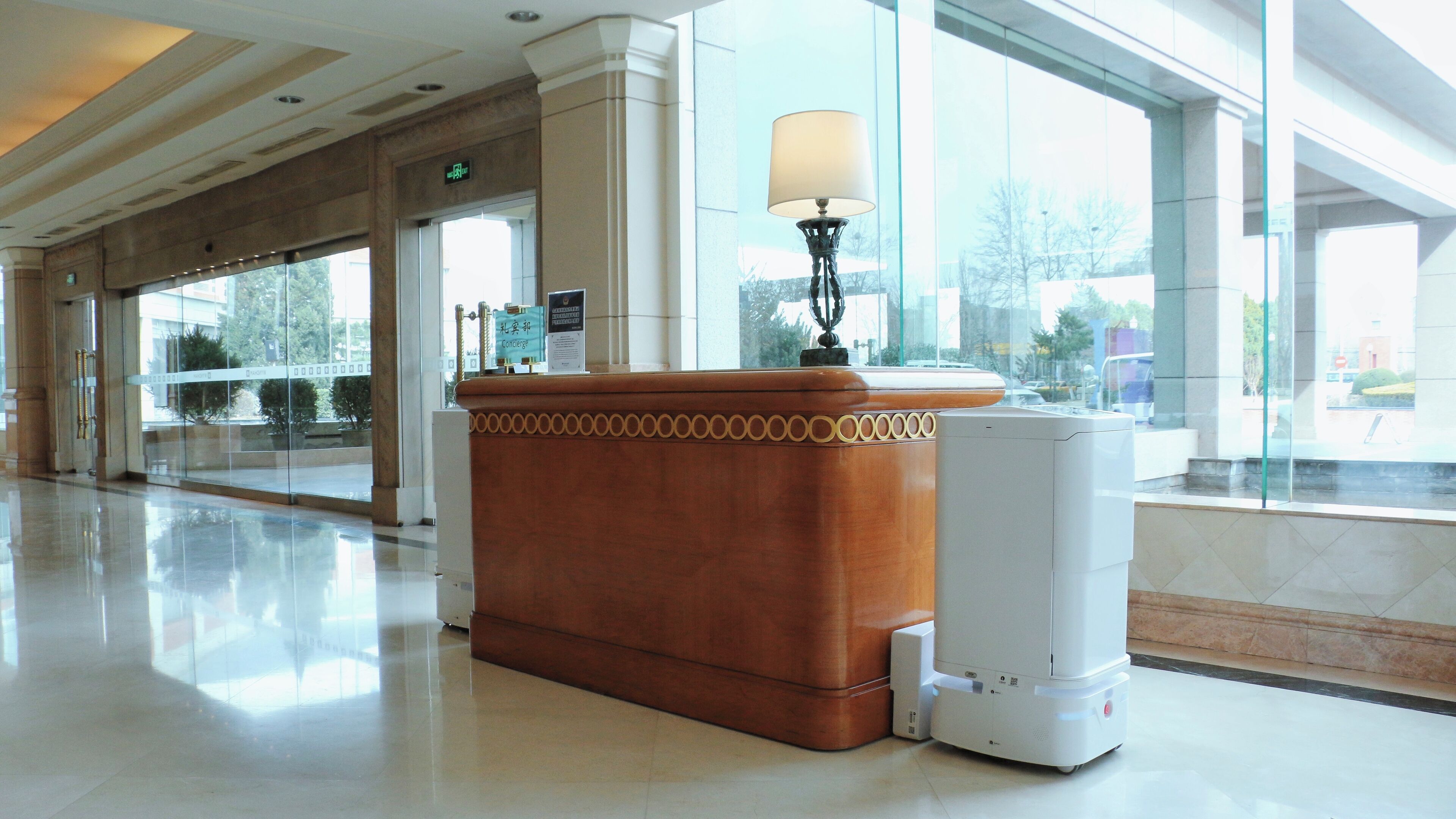 A lobby with a reception desk, a lamp, and a white speaker.