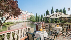 A terrace with outdoor seating, a view of a river, and a building in the background. - Wyndham Beijing North Hotel (Beijing)