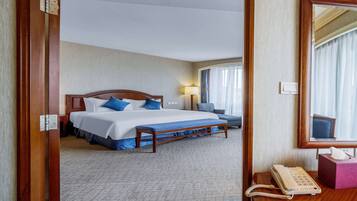 Een hotelkamer met een groot bed, een nachtkastje met telefoon, lamp en spiegel.