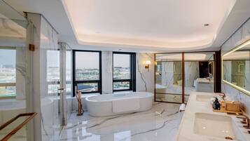 Une salle de bain moderne avec une grande baignoire, deux lavabos et un grand miroir.