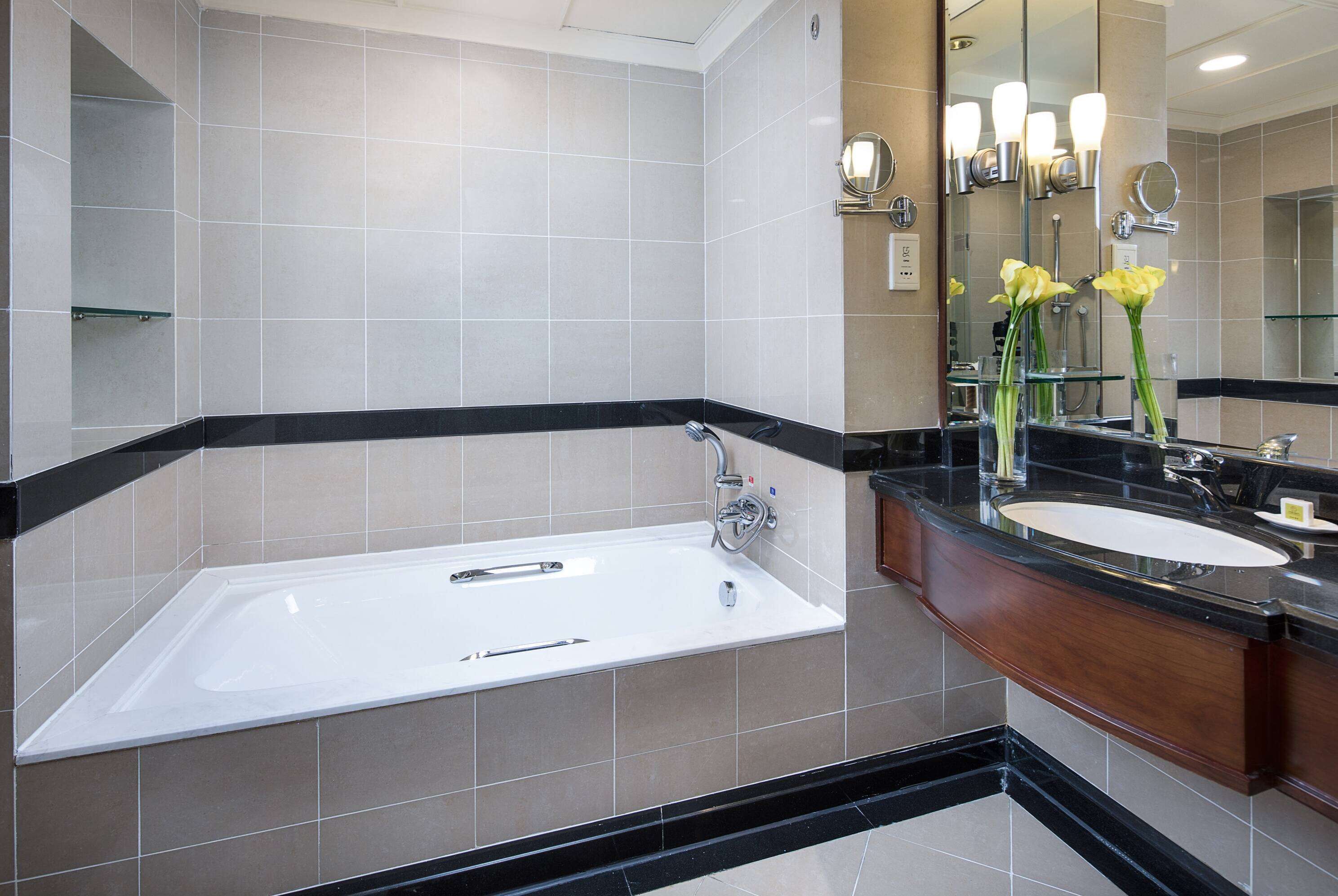 Un baño moderno con una bañera independiente, un tocador con lavamanos y un espejo grande.