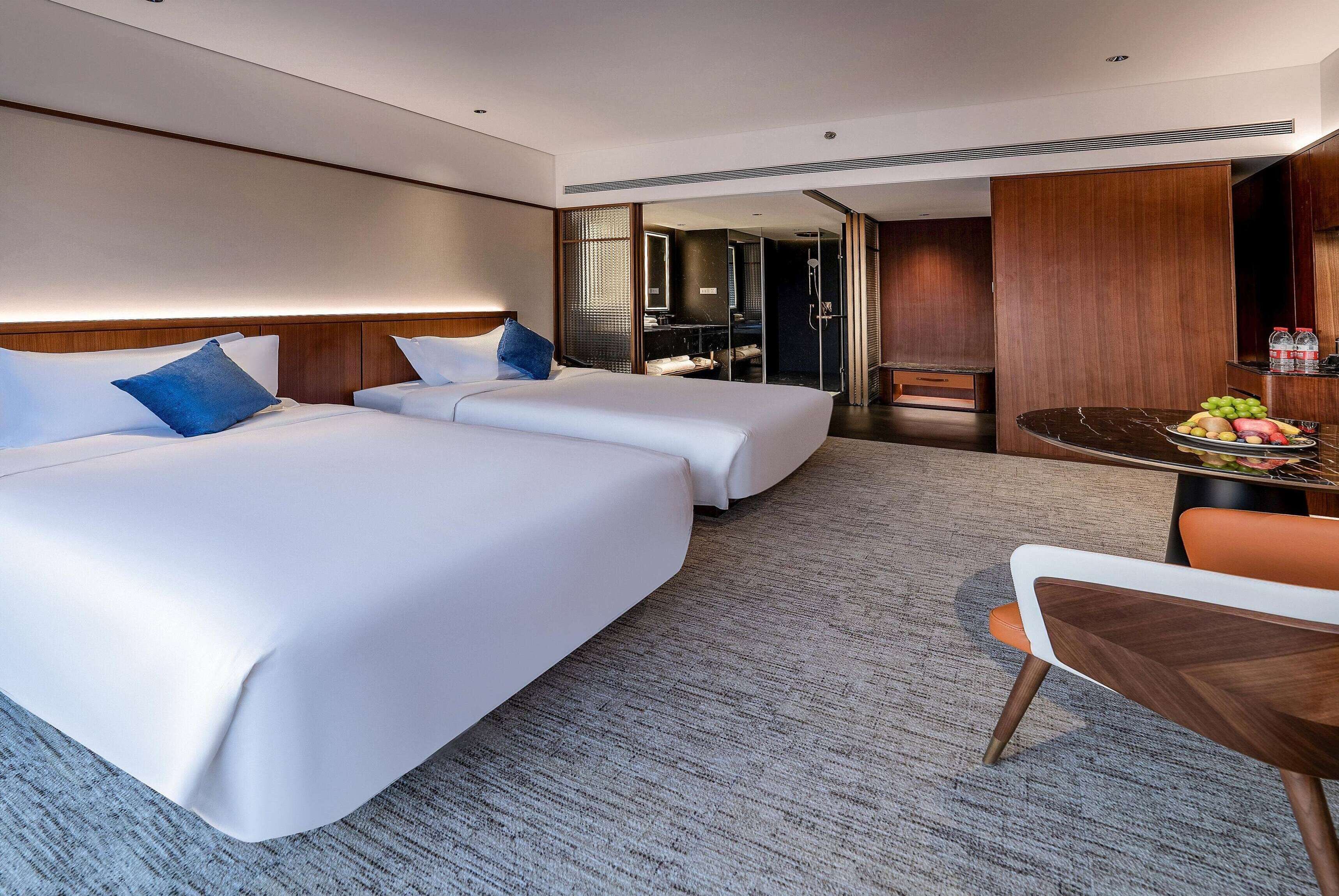 Een hotelkamer met twee bedden, een klein tafeltje met fruit en een zithoek.