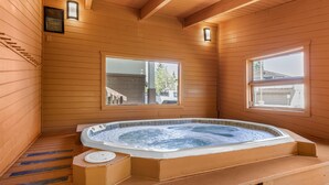 Un spa con sala de madera, bañera de hidromasaje, paredes de madera y ventanas amplias.