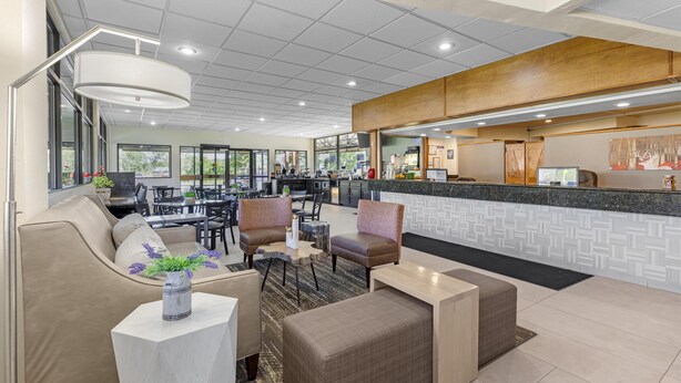 Un moderno vestíbulo de hotel con una zona de estar, un mostrador de recepción y una cocina al fondo.