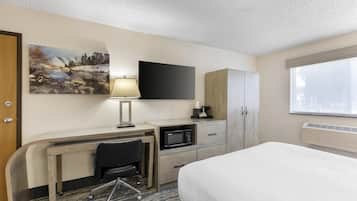 A hotel room with a bed, desk, chair, TV, cabinet, and a painting on the wall.