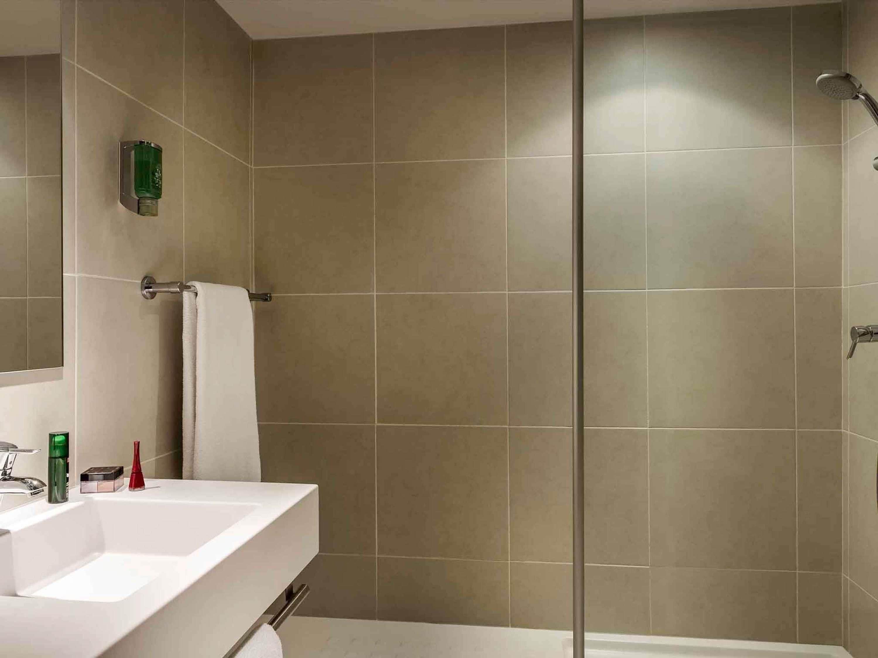 A modern bathroom with a shower, a sink, and a mirror.