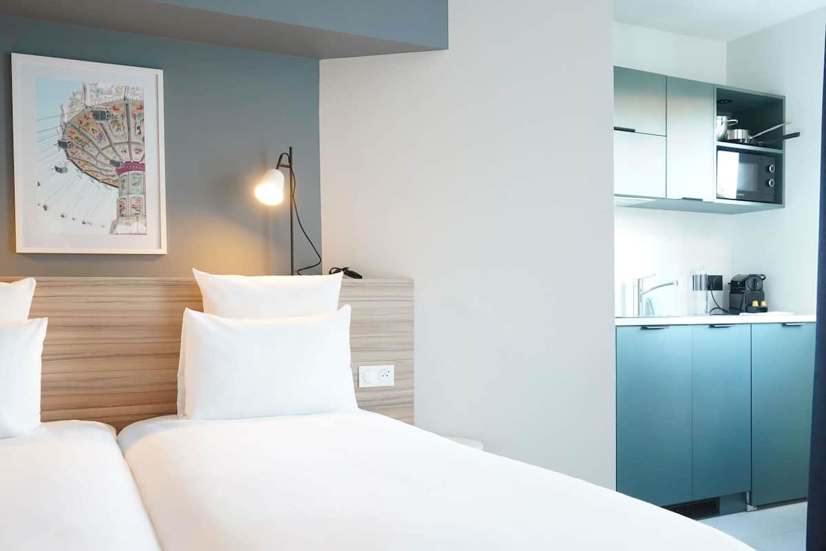 A hotel room with a bed, a desk, and a kitchenette.
