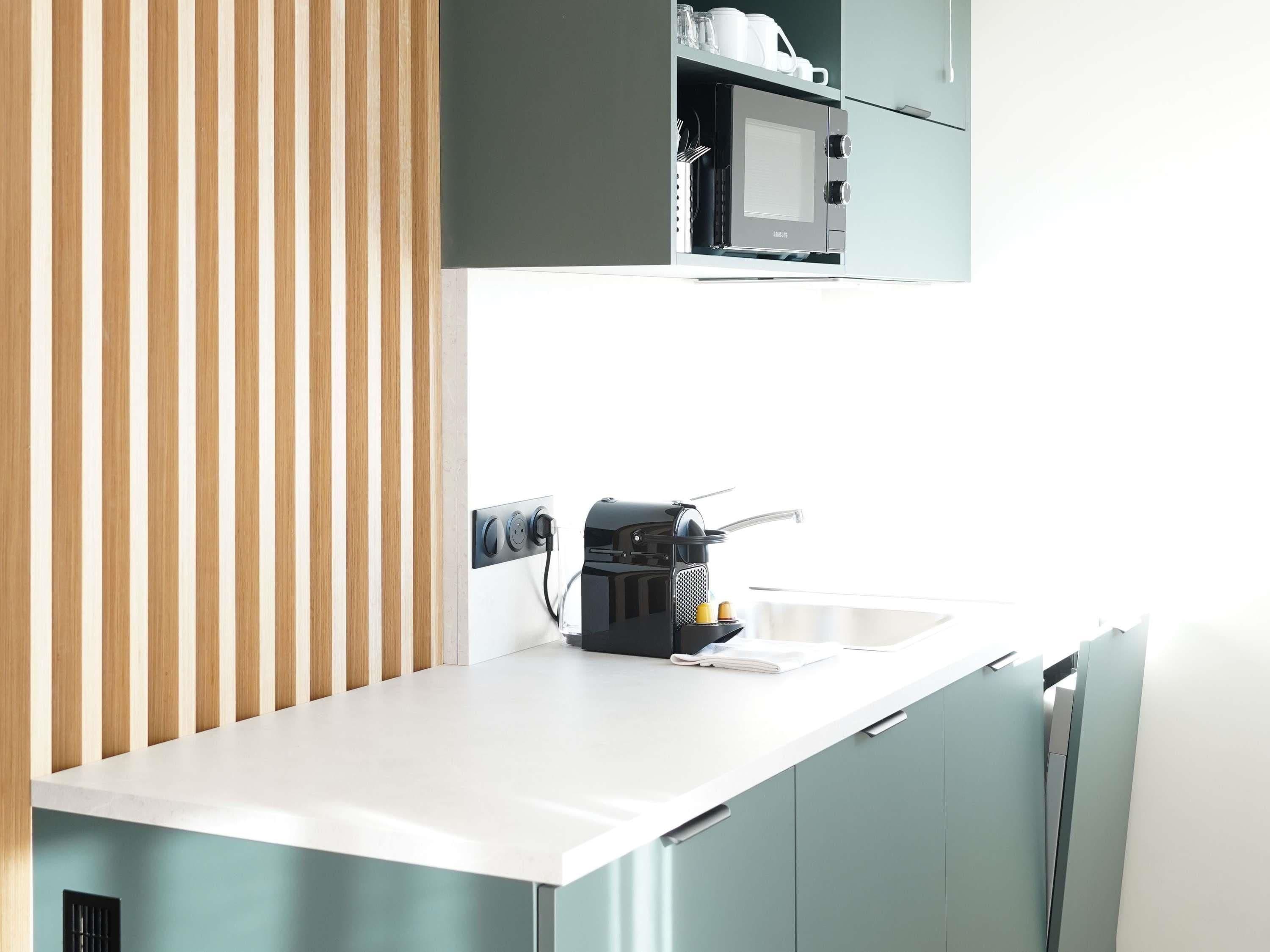 Eine moderne Küche mit integrierter Kaffeemaschine, Mikrowelle und Wasserkocher auf der Arbeitsfläche.