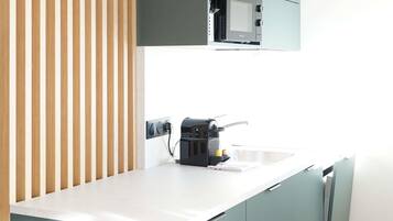 Eine moderne Küche mit integrierter Kaffeemaschine, Mikrowelle und Wasserkocher auf der Arbeitsfläche.