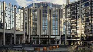 A modern hotel with a glass facade, large columns, and a prominent entrance.