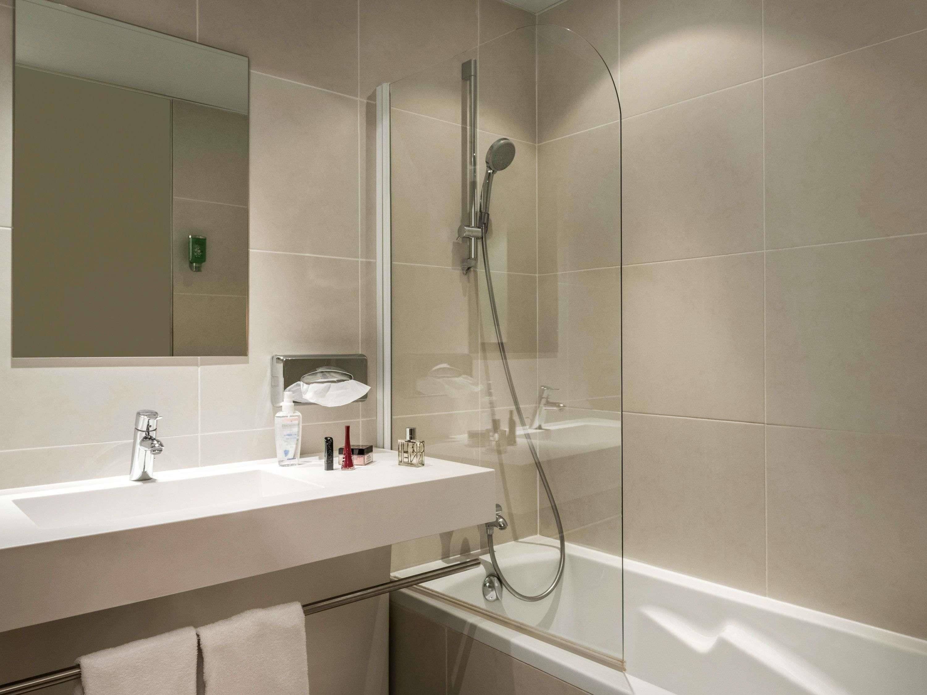 A modern bathroom with a glass-enclosed shower, a white sink, and a mirror above it.