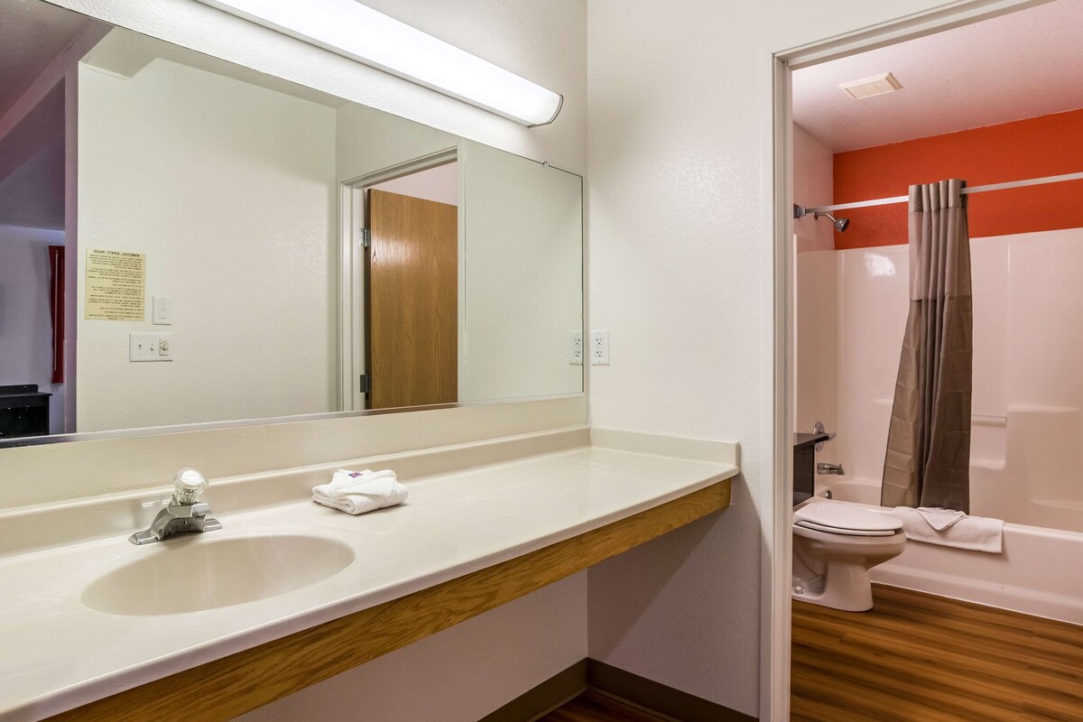 A bathroom with a white sink, mirror, and a shower with a curtain.