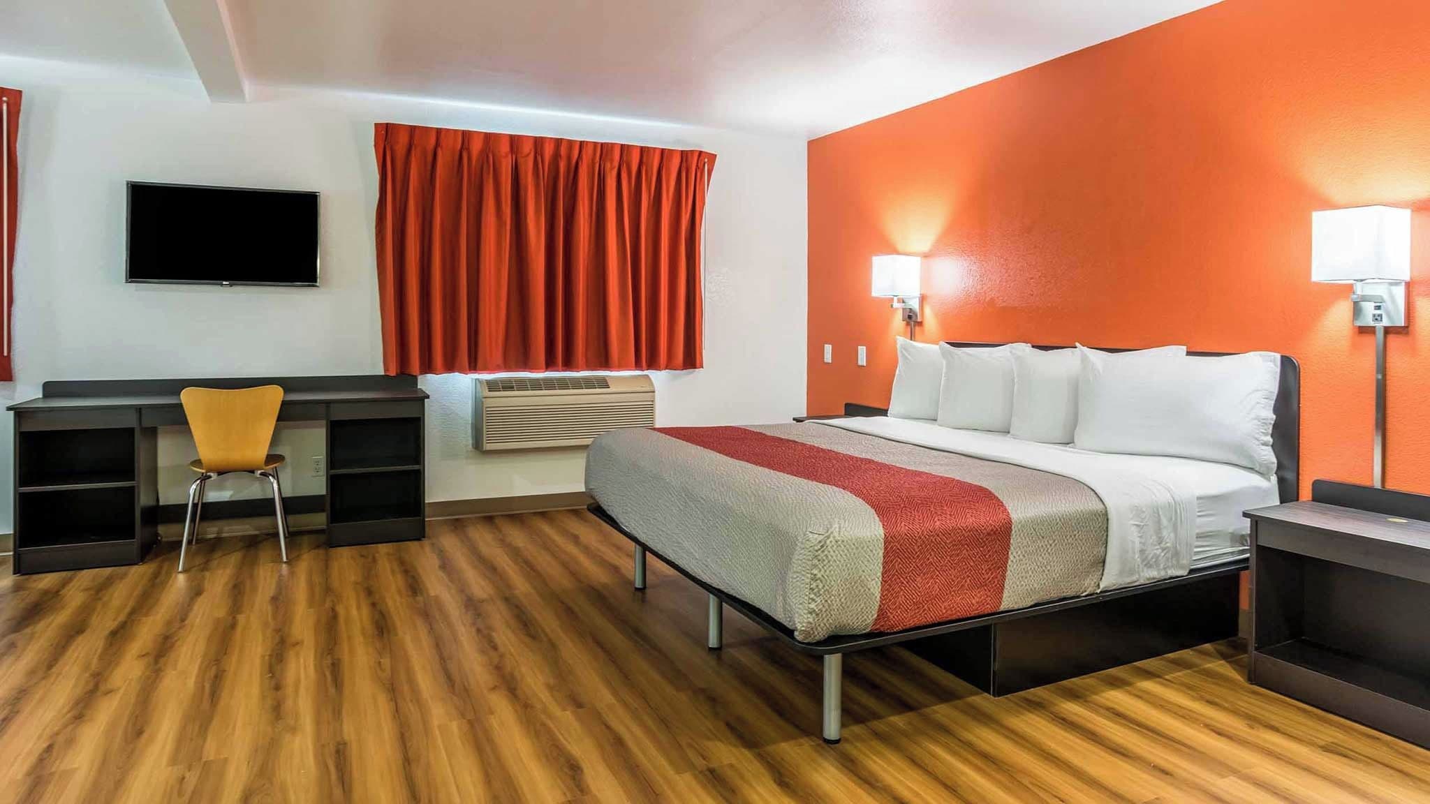 Habitación de hotel con cama, escritorio, silla y equipo de aire acondicionado.