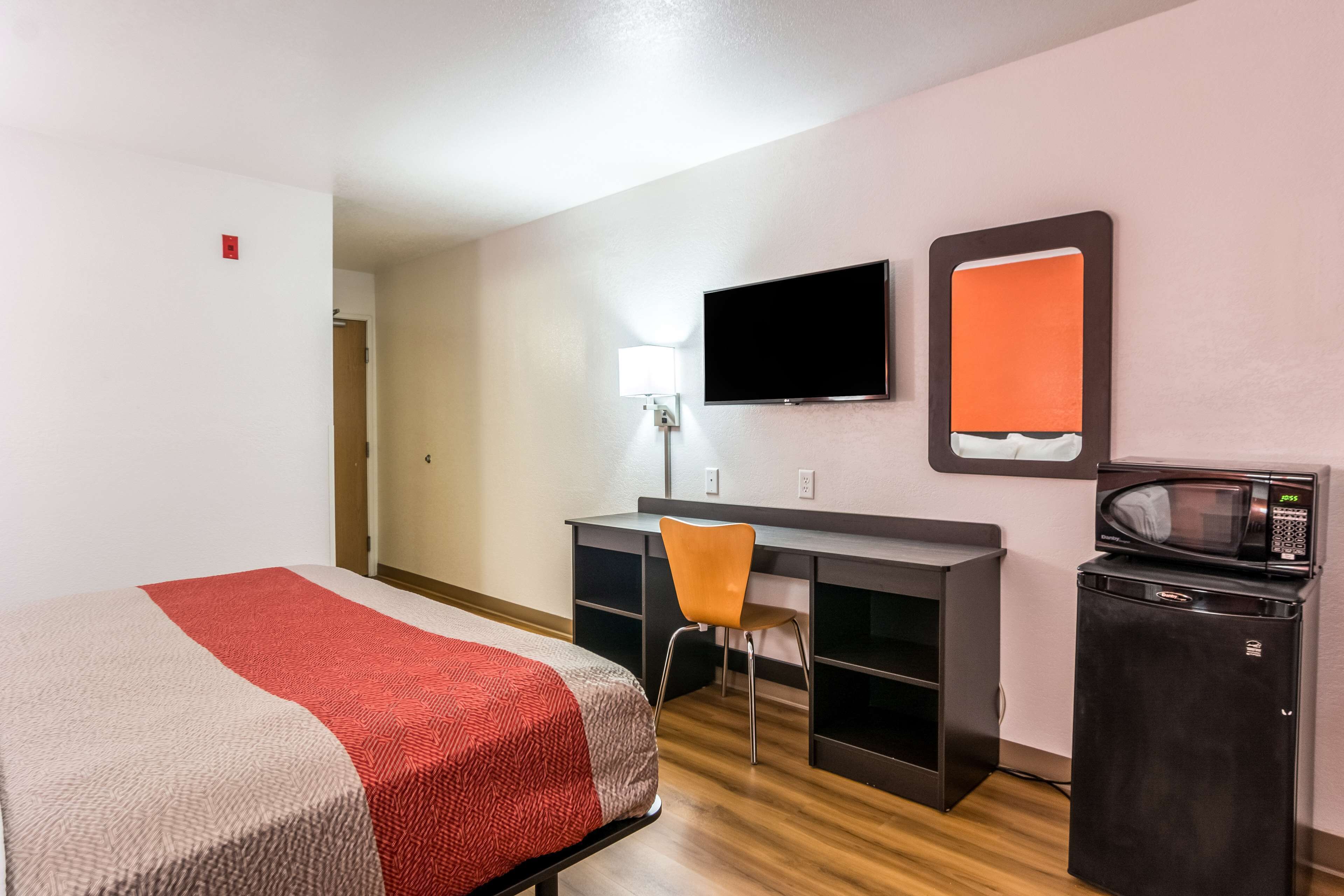 Hotelkamer met een bed, bureau, stoel, televisie, magnetron en kleine koelkast.