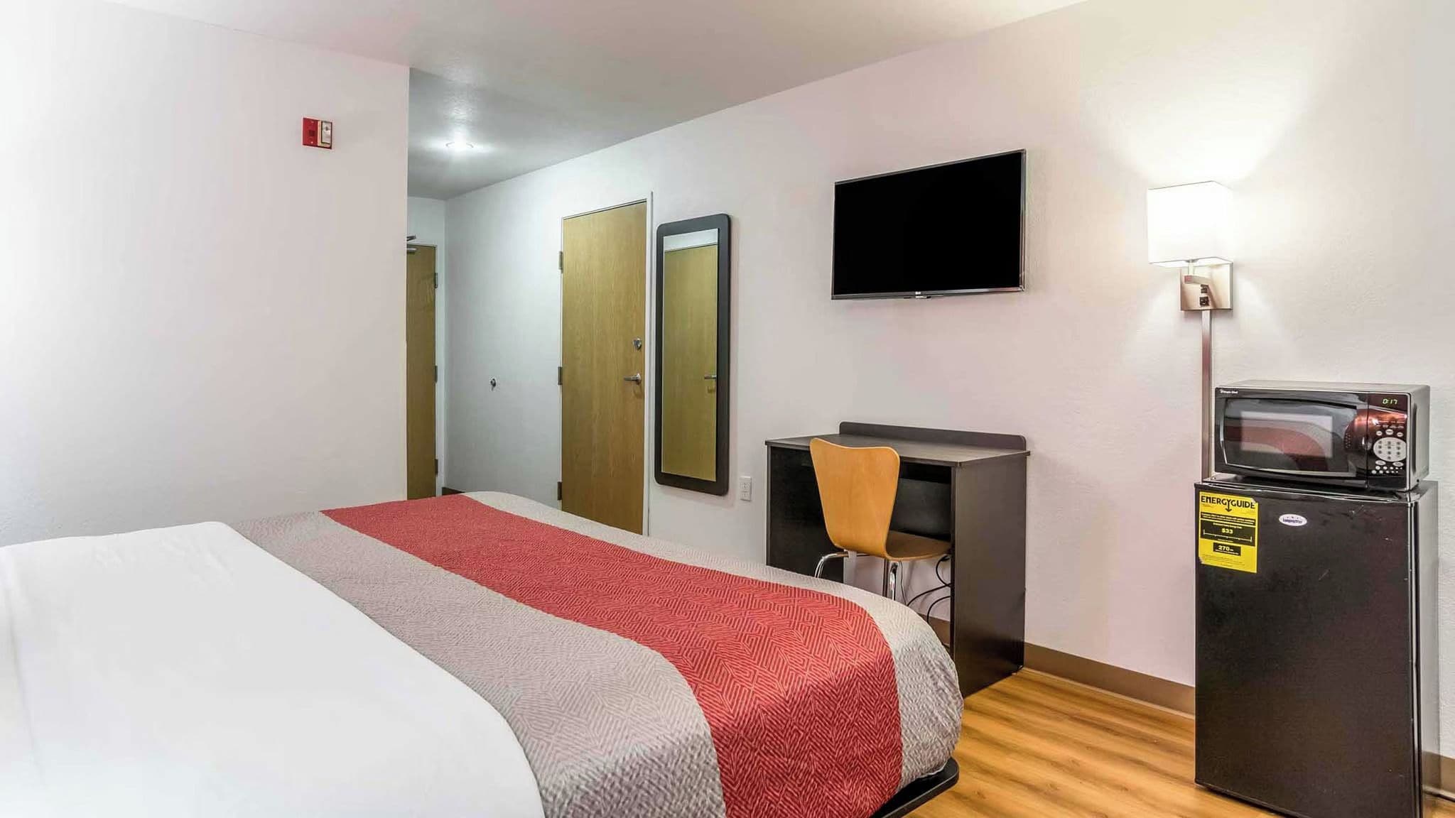 Ein Hotelzimmer mit einem Bett, einem Schreibtisch, einem Sessel, einem Fernseher und einem Kühlschrank.