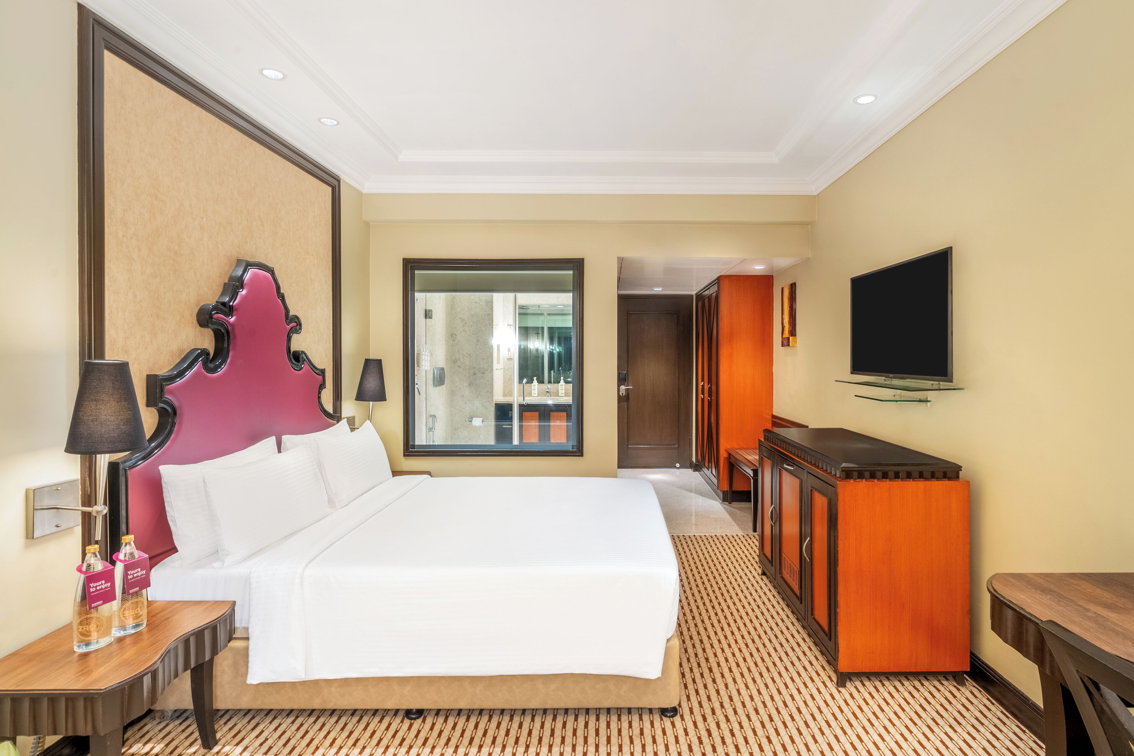 Una habitación de hotel con una cama grande, televisión, escritorio y armario.