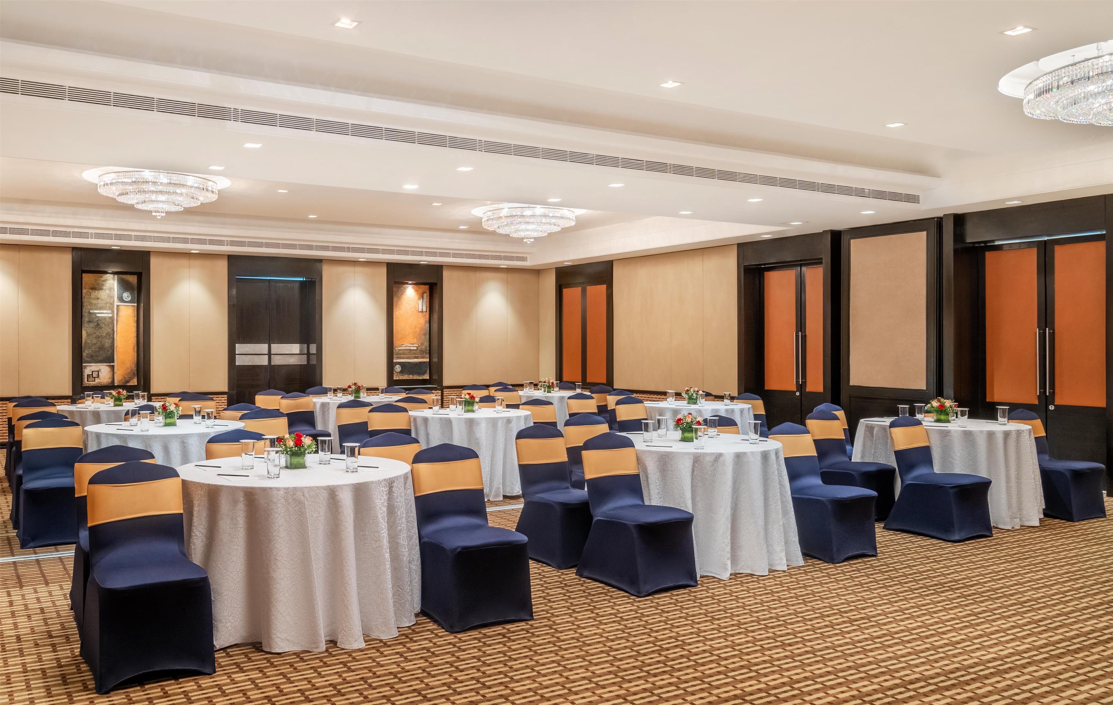 A conference room with round tables, chairs, and chandeliers.