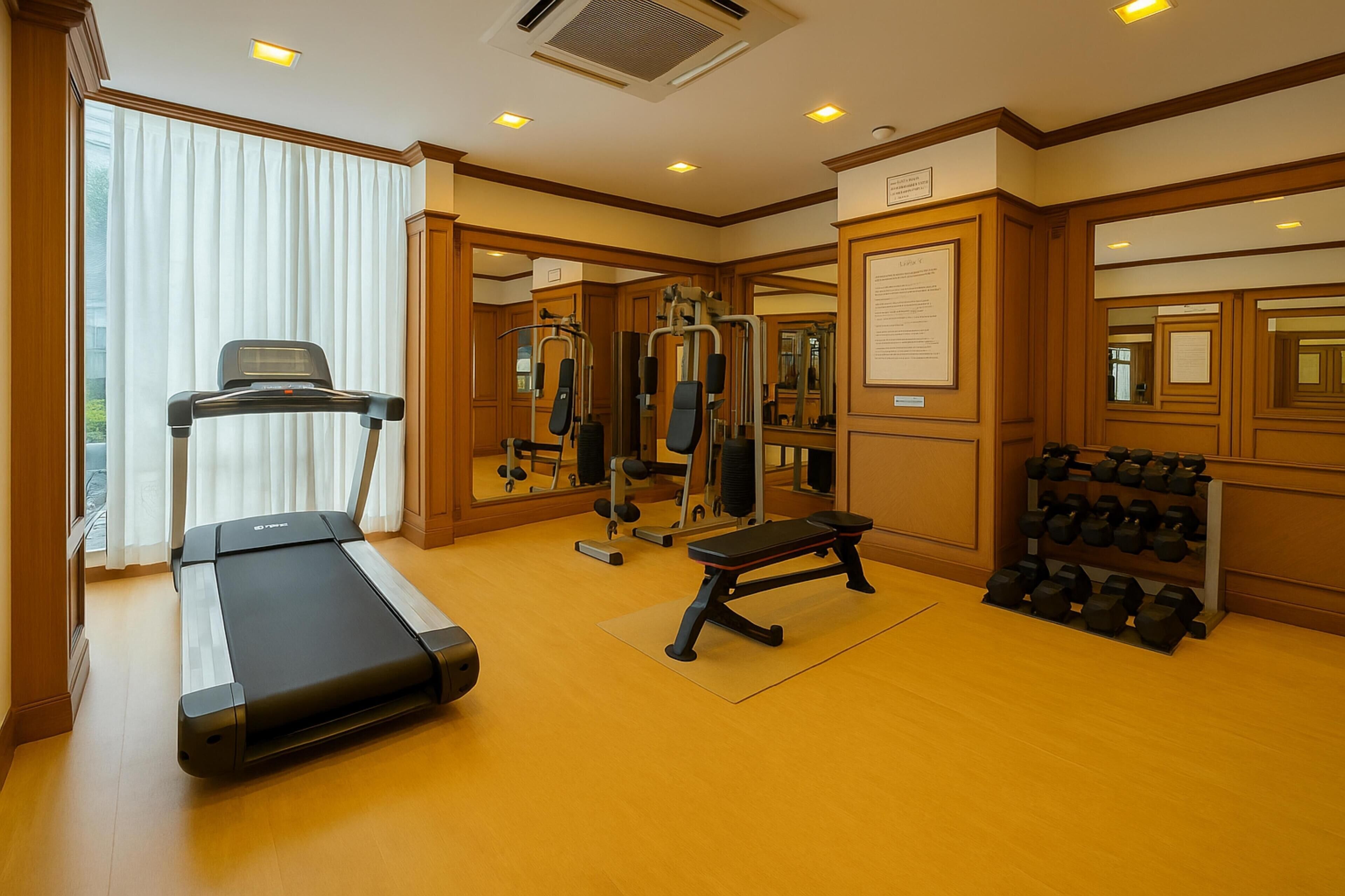 Une salle de sport équipée d’un tapis de course, d’un banc, d’un banc de musculation et d’haltères.