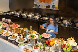 A buffet with various dishes and a person serving food. - St. Marks Hotel Bengaluru, a member of Radisson Individuals (Bengaluru)