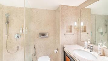 A modern bathroom with a glass-enclosed shower, a white toilet, and a vanity with a large mirror and sink.